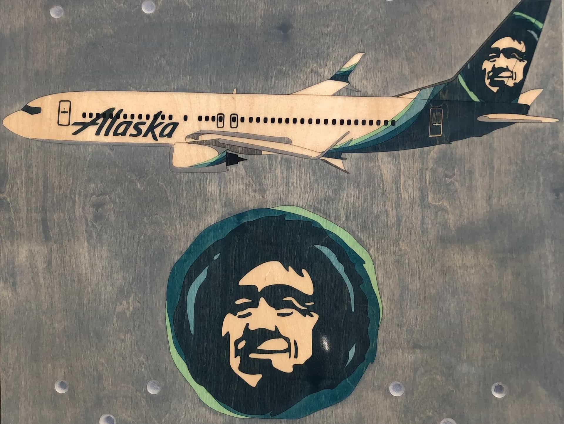 Close-up of a YoreBoard cornhole board with a hand-stained Alaska Airlines plane and pilot's face.