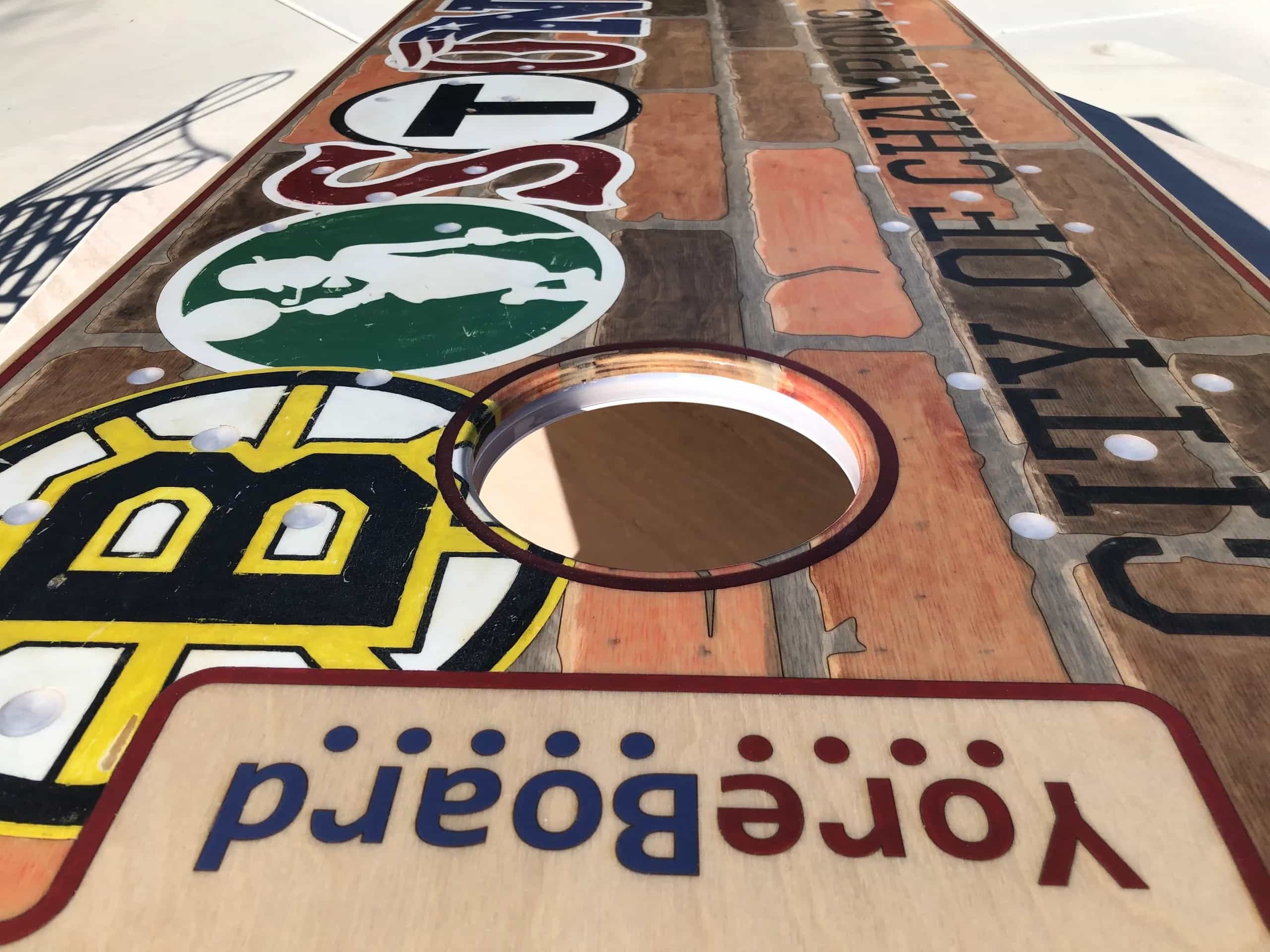 Detailed shot of a YoreBoard cornhole board highlighting its custom hand-stained Boston sports and city graphics.