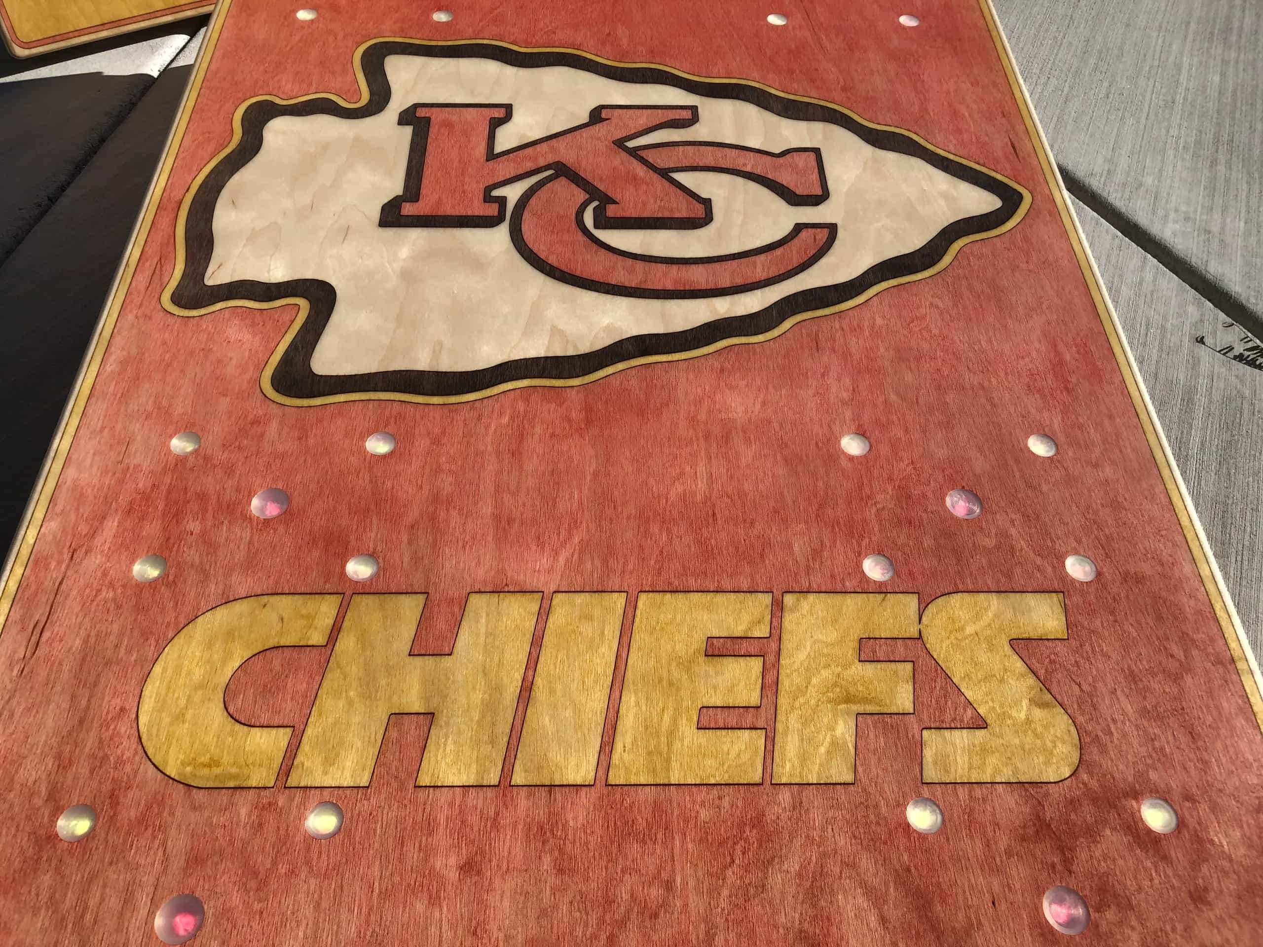 A close-up view of a YoreBoard cornhole board surface, showcasing a large, hand-stained Kansas City Chiefs arrowhead logo and 'CHIEFS' text in red and yellow.