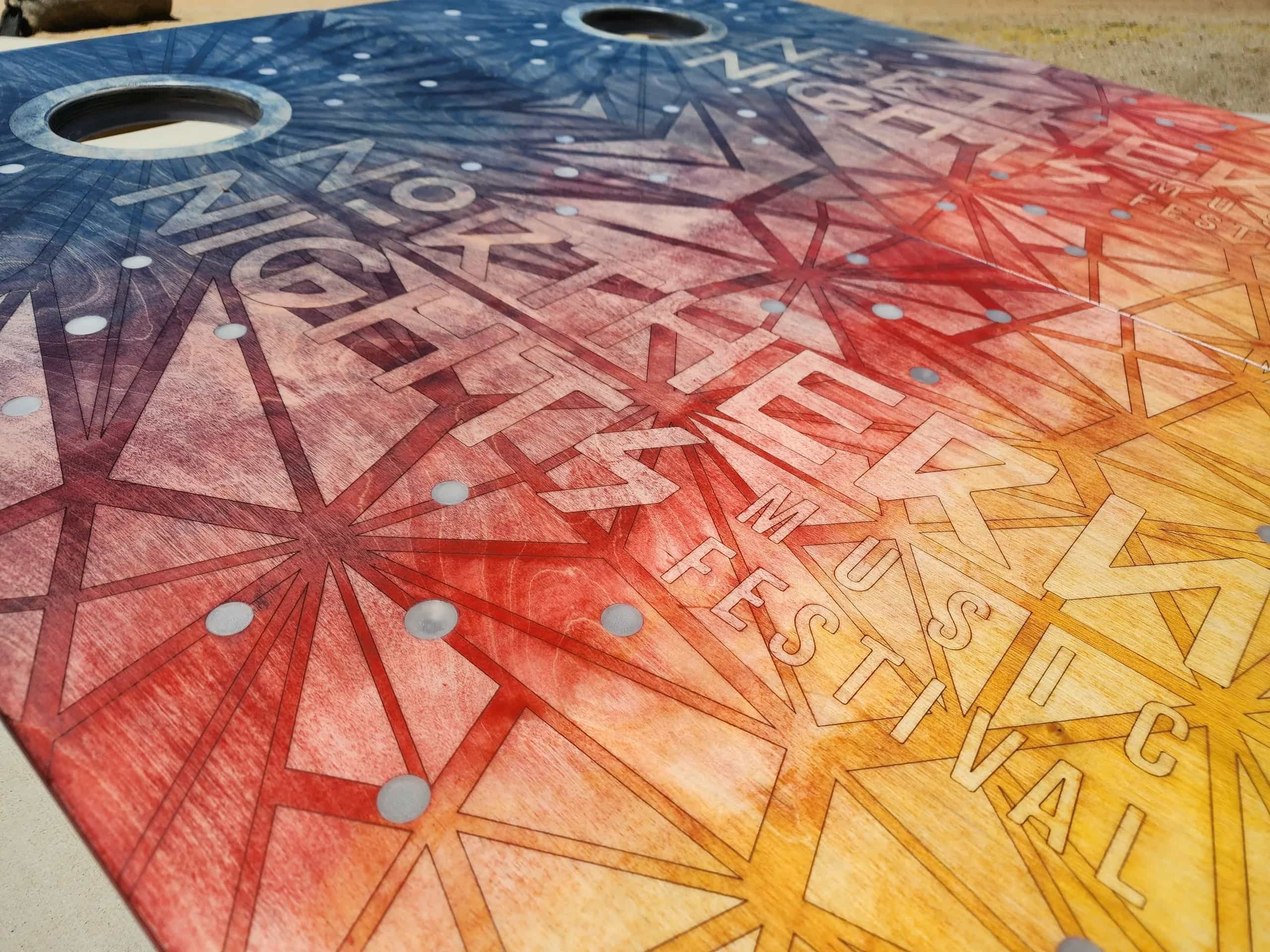 Detailed shot of a YoreBoard cornhole board highlighting its intricate hand-stained festival artwork with a dynamic color gradient.