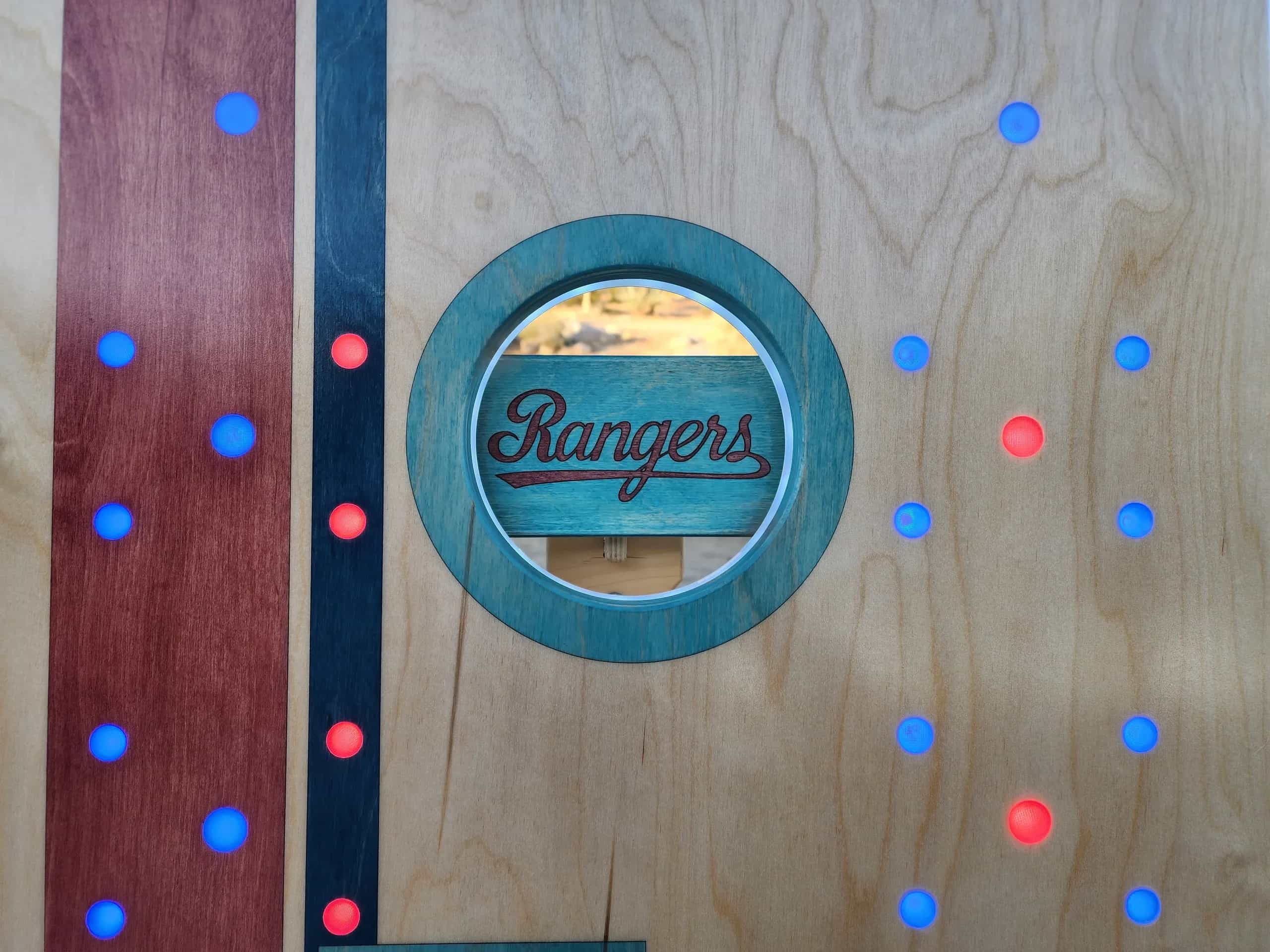 Detailed shot of a YoreBoard cornhole board highlighting the custom hand-stained 'Rangers' text on the leg support within the cornhole opening,
