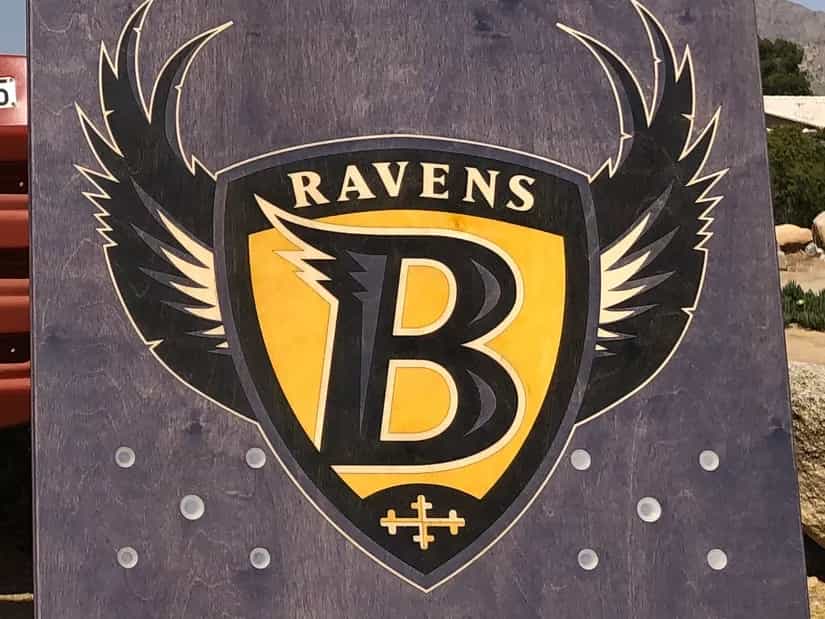Close-up of a YoreBoard cornhole board with a hand-stained Baltimore Ravens logo.