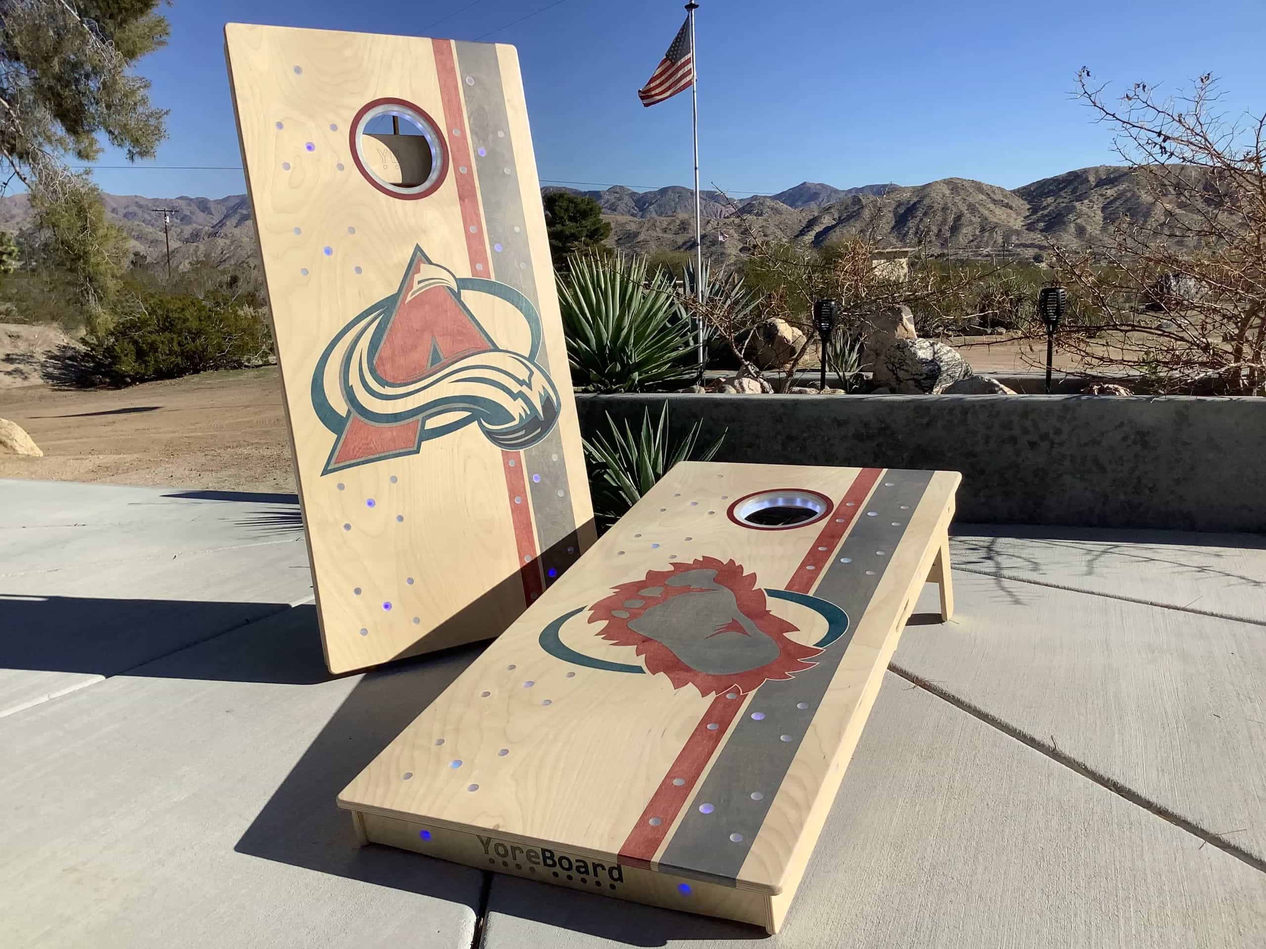 A pair of YoreBoard cornhole boards showcasing detailed hand-stained Colorado Avalanche hockey team graphics, designed for fans to enjoy outdoor games.