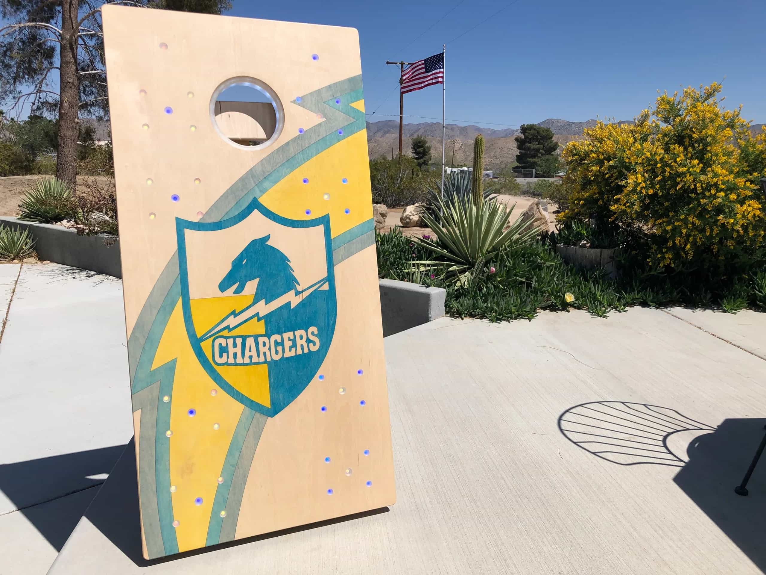 A YoreBoard cornhole board showcasing a vibrant, hand-stained Los Angeles Chargers football team design with blue and yellow accents, ideal for game day tailgating.