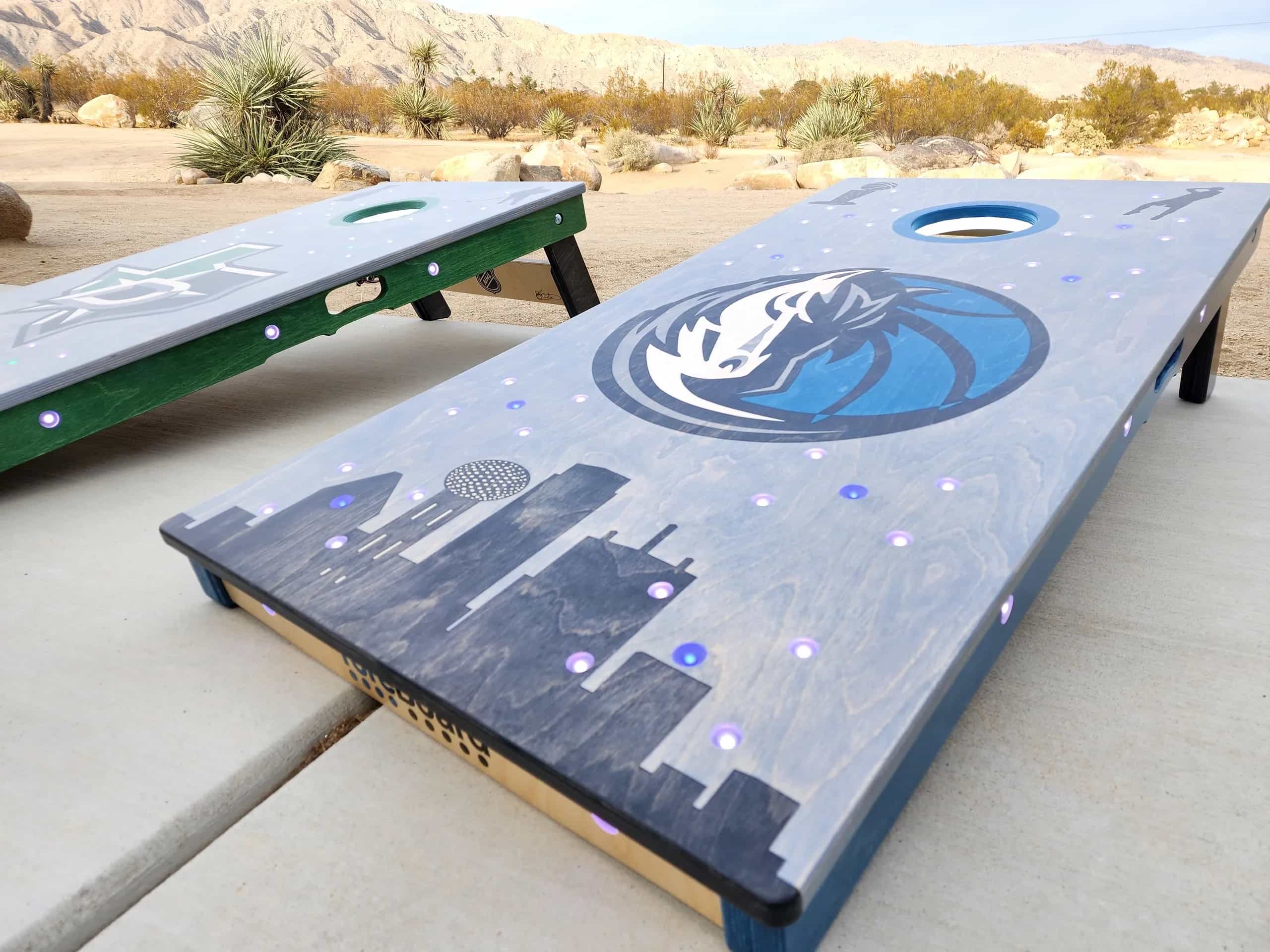 Personalized YoreBoard cornhole boards celebrating Dallas sports with Stars and Mavericks logos, city skyline graphics, and integrated Scoring LEDs.