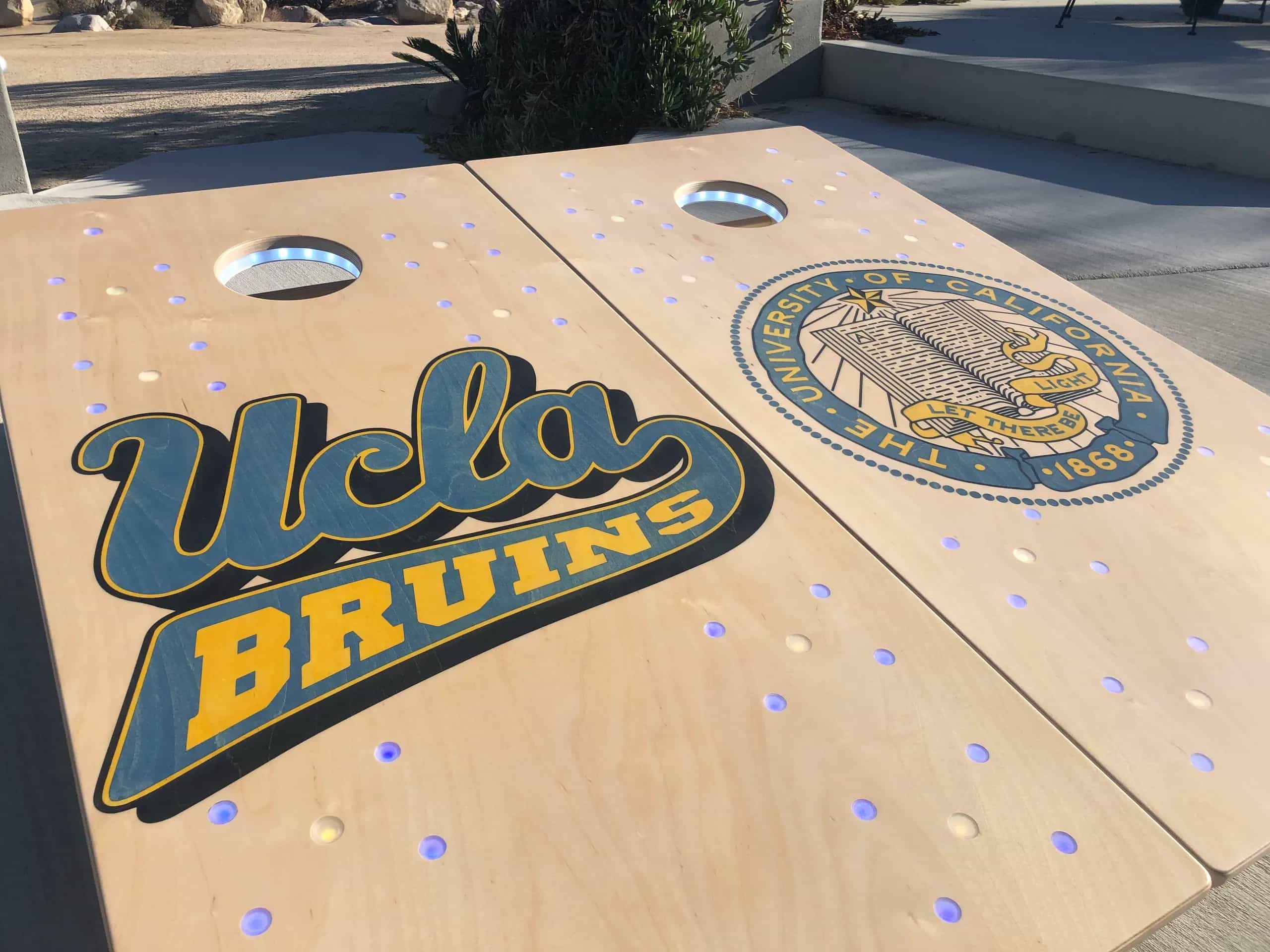 A pair of YoreBoard cornhole boards showcasing detailed hand-stained UCLA university graphics in blue and gold, designed for alumni or fans.