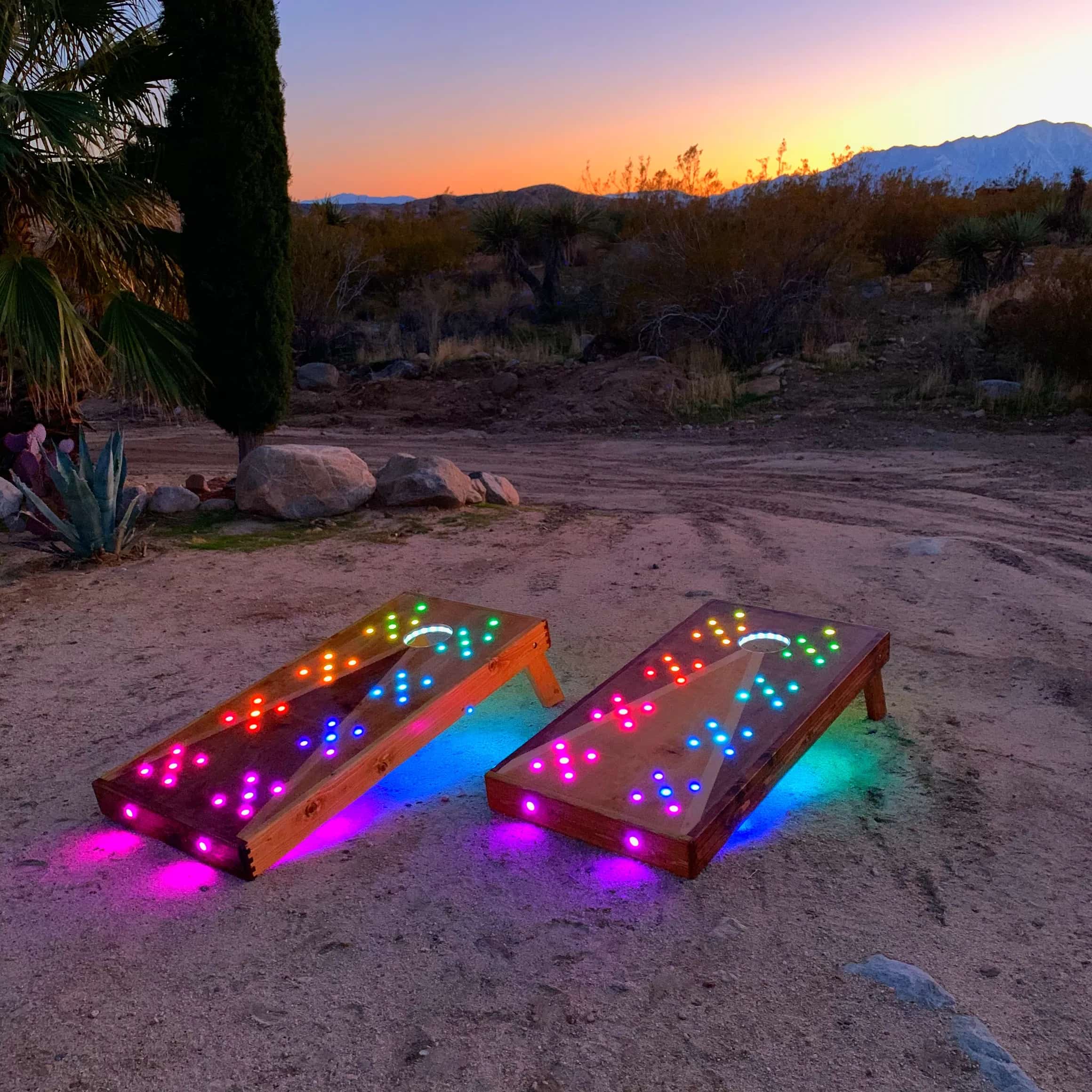 Outdoor YoreBoard cornhole boards showcasing their impressive array of colorful Scoring LEDs and atmospheric under-lighting, ideal for night games in a natural setting.